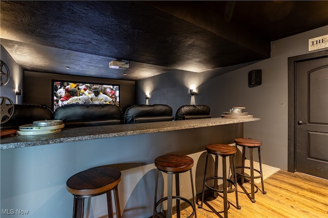 home theater with bar area and light hardwood / wood-style flooring