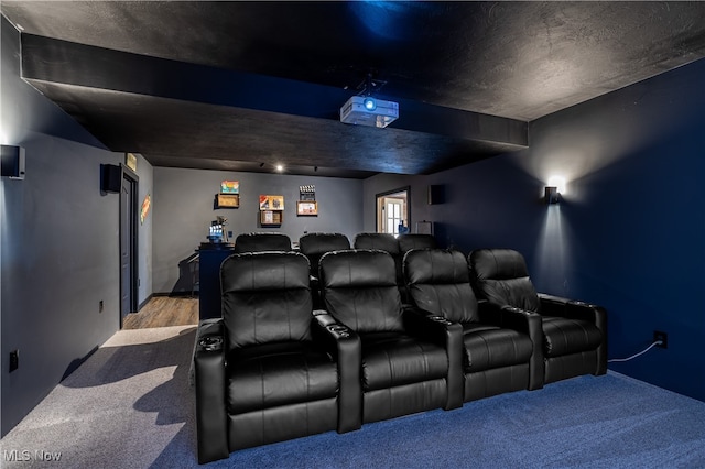 carpeted cinema room with beamed ceiling and a textured ceiling