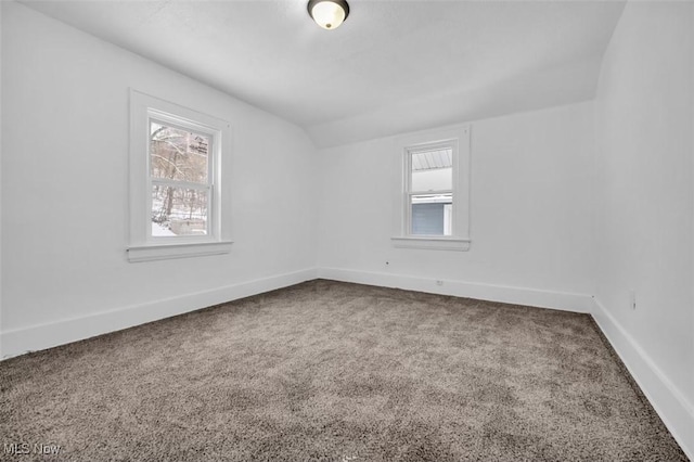 unfurnished room featuring carpet, a healthy amount of sunlight, vaulted ceiling, and baseboards