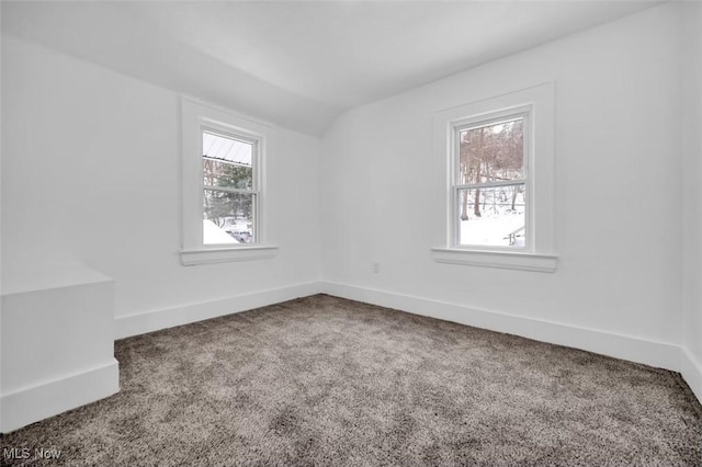 unfurnished room featuring carpet floors, plenty of natural light, vaulted ceiling, and baseboards