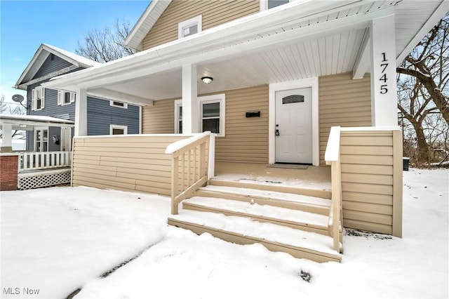 snow covered property entrance featuring covered porch