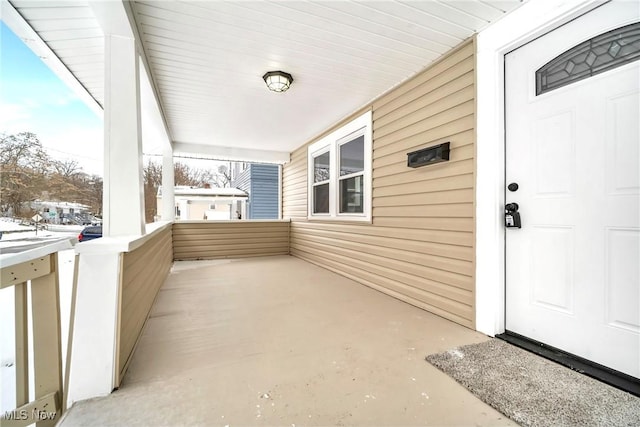 snow covered property entrance with a porch