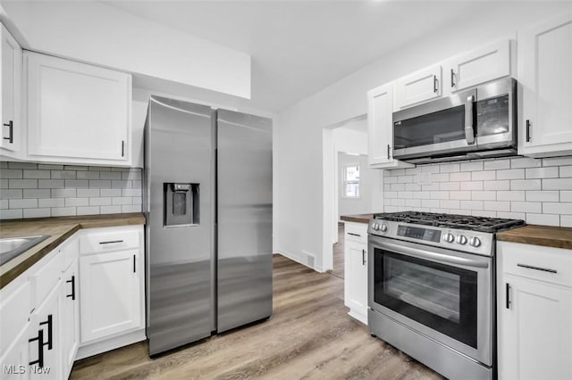 kitchen with appliances with stainless steel finishes, wood counters, light wood-style flooring, and white cabinets