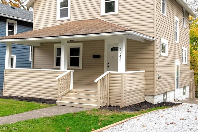 doorway to property with covered porch and a shingled roof