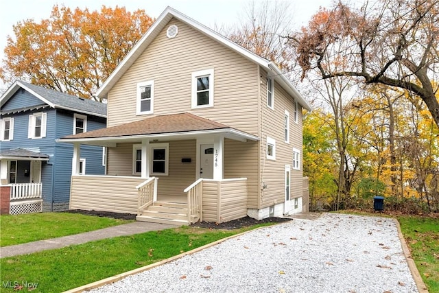 american foursquare style home featuring covered porch and a front yard