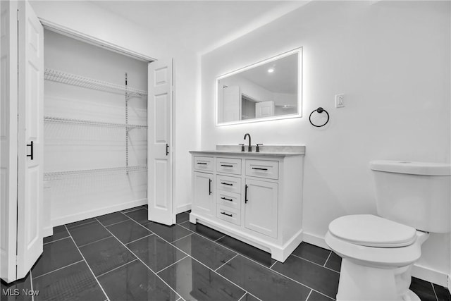 bathroom featuring toilet, tile patterned flooring, baseboards, and vanity