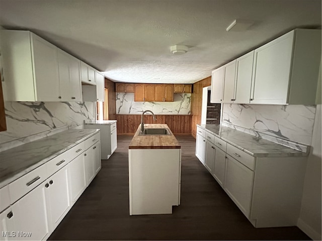 kitchen with a center island with sink, white cabinetry, dark wood-type flooring, and sink