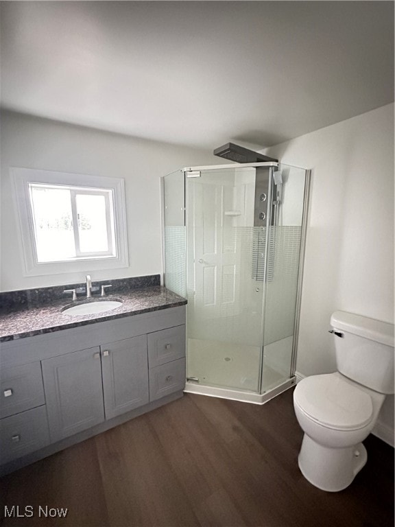 bathroom featuring hardwood / wood-style flooring, vanity, toilet, and an enclosed shower