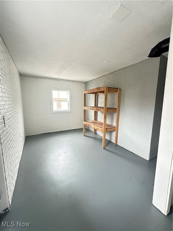 basement with brick wall and a textured ceiling