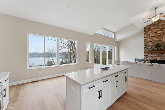 kitchen with white cabinets, plenty of natural light, a water view, and light hardwood / wood-style floors