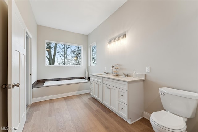 bathroom featuring a bath, wood-type flooring, vanity, and toilet