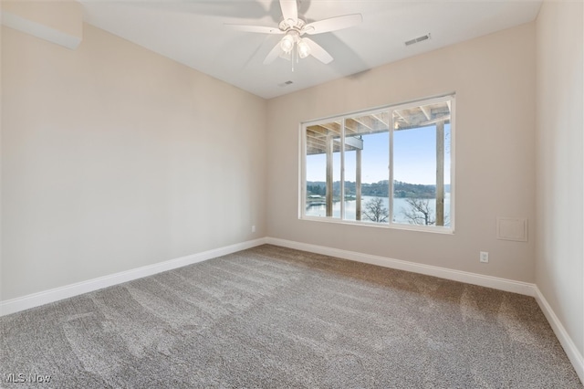 unfurnished room featuring carpet, ceiling fan, and a water view