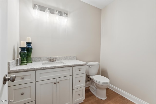 bathroom featuring wood-type flooring, vanity, and toilet