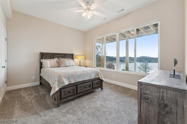 carpeted bedroom with ceiling fan and a water view