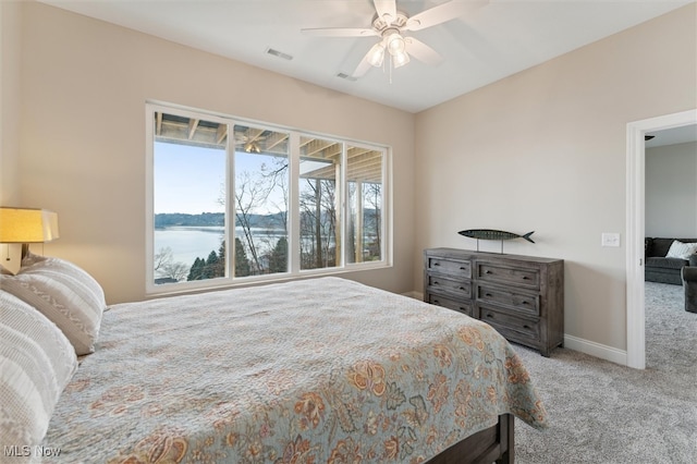 bedroom with carpet, a water view, and ceiling fan