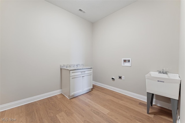 clothes washing area with electric dryer hookup, light hardwood / wood-style floors, and washer hookup