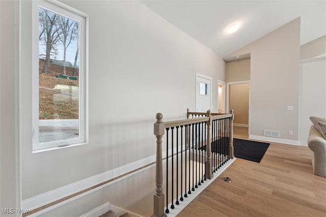 hallway featuring lofted ceiling, a wealth of natural light, and light hardwood / wood-style flooring