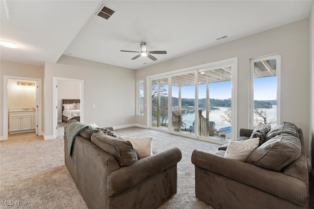 carpeted living room with a water view and ceiling fan