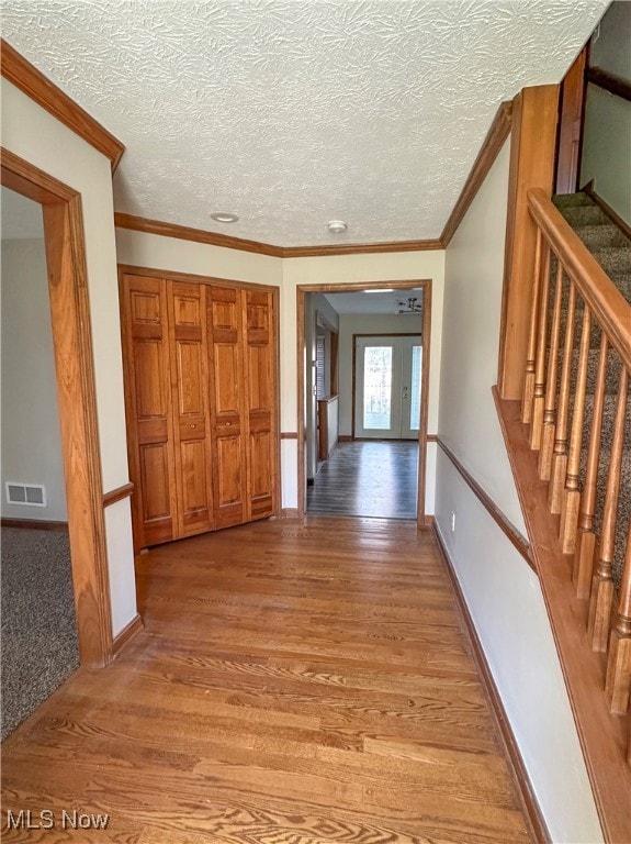 hallway with crown molding, light hardwood / wood-style floors, and a textured ceiling