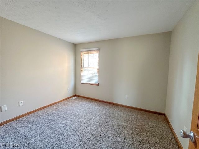 carpeted empty room featuring a textured ceiling