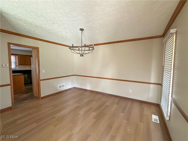 unfurnished dining area with a textured ceiling, light wood-type flooring, and ornamental molding