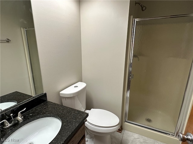 bathroom with tile patterned flooring, vanity, toilet, and walk in shower