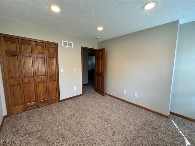 unfurnished bedroom with a textured ceiling, carpet floors, and a closet