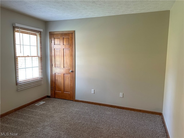 unfurnished room with carpet flooring and a textured ceiling