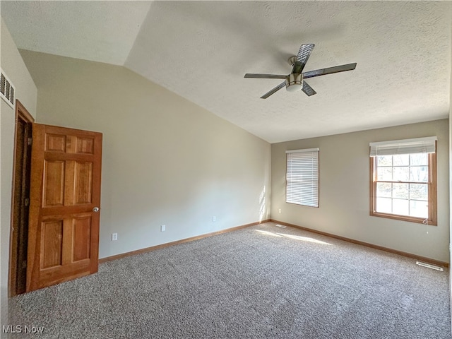 carpeted empty room with a textured ceiling, ceiling fan, and vaulted ceiling