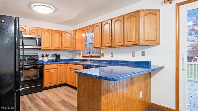 kitchen with sink, light hardwood / wood-style flooring, backsplash, kitchen peninsula, and black appliances