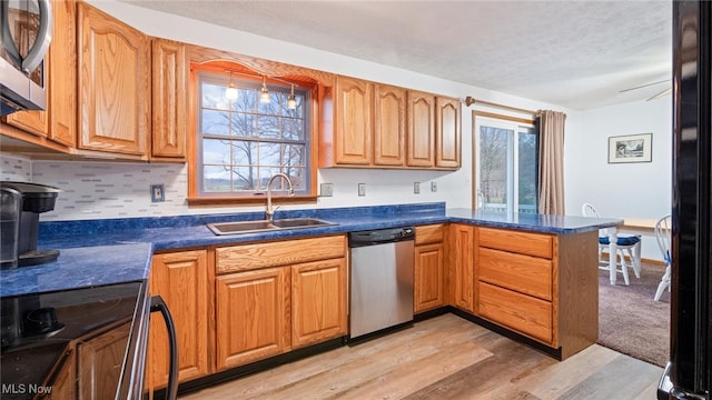 kitchen with backsplash, sink, light hardwood / wood-style flooring, kitchen peninsula, and stainless steel appliances