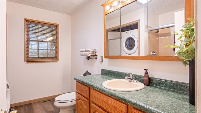 bathroom with vanity, a textured ceiling, hardwood / wood-style floors, washer / clothes dryer, and a shower with shower door