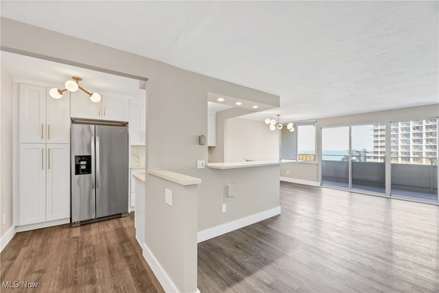 kitchen featuring kitchen peninsula, an inviting chandelier, stainless steel fridge with ice dispenser, dark hardwood / wood-style floors, and white cabinetry