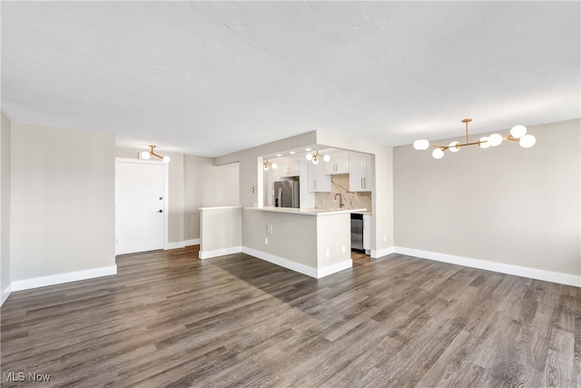 unfurnished living room with sink, dark wood-type flooring, and a notable chandelier