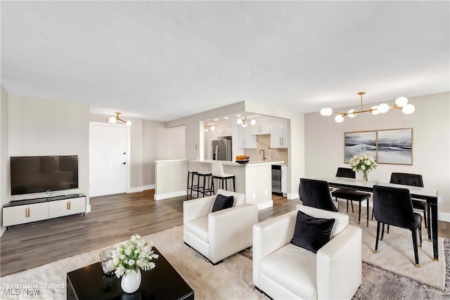 living room featuring light wood-type flooring, sink, and an inviting chandelier