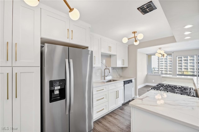 kitchen with white cabinetry, sink, stainless steel appliances, and light stone counters