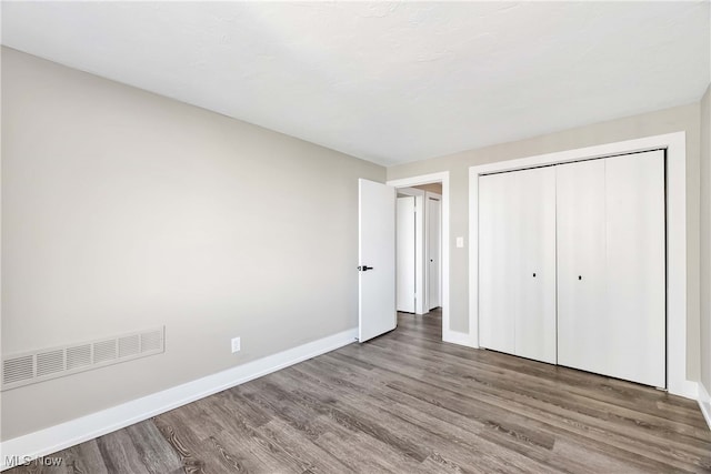 unfurnished bedroom with a closet and hardwood / wood-style flooring