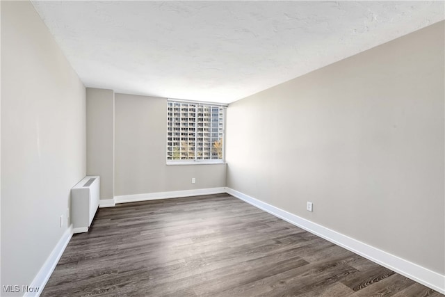 unfurnished room featuring radiator and dark hardwood / wood-style floors