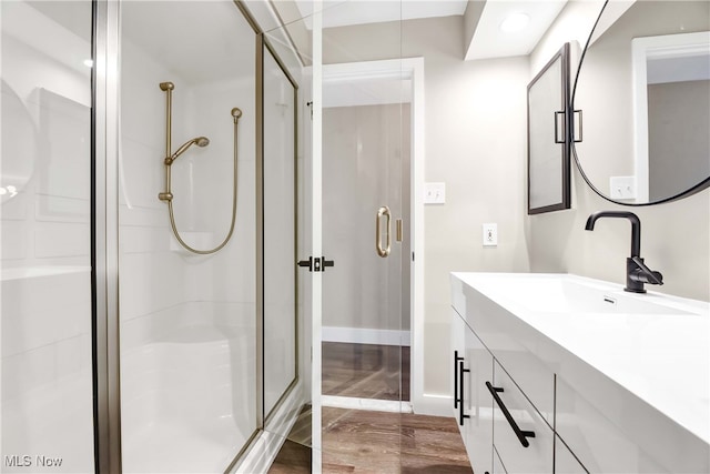 bathroom featuring hardwood / wood-style floors, vanity, and a shower with shower door