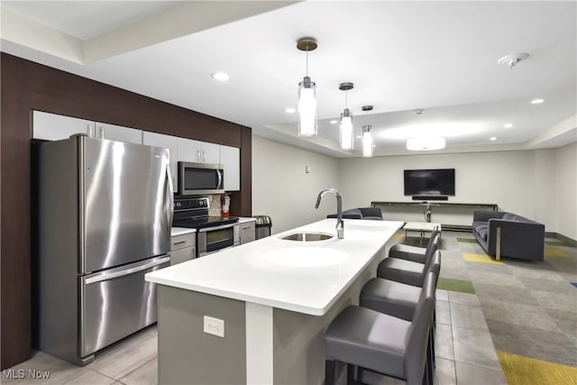 kitchen featuring appliances with stainless steel finishes, a breakfast bar, sink, hanging light fixtures, and an island with sink