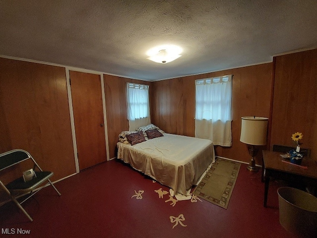 bedroom with carpet, wood walls, and a textured ceiling