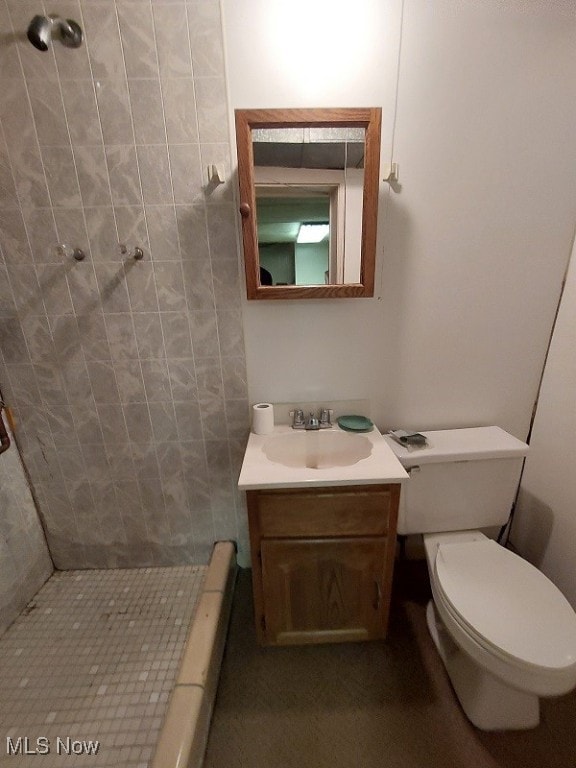 bathroom featuring vanity, toilet, and a tile shower