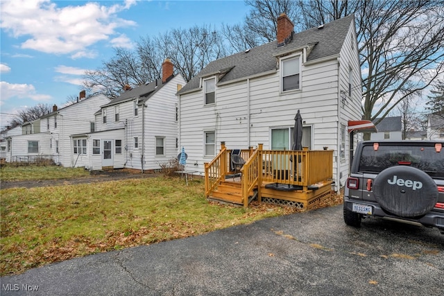 back of property with a lawn and a deck