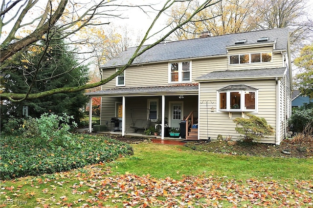 back of house with a lawn and covered porch