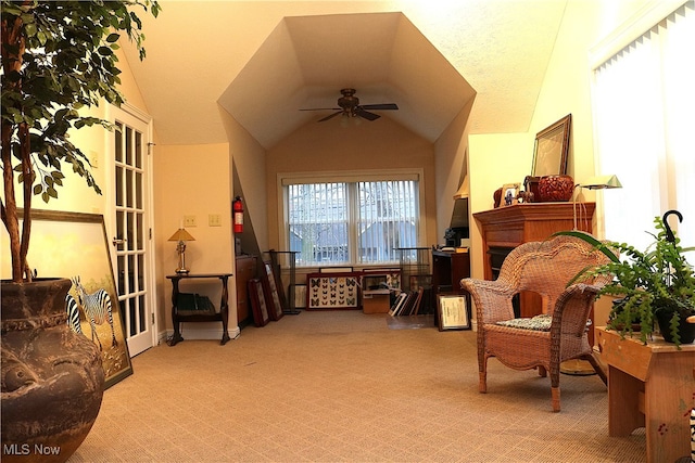 living area with light carpet, a textured ceiling, vaulted ceiling, and ceiling fan