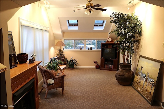 sitting room with carpet, ceiling fan, lofted ceiling with skylight, and rail lighting