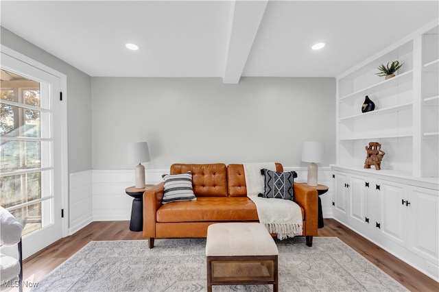 sitting room with hardwood / wood-style flooring, built in shelves, a healthy amount of sunlight, and beamed ceiling