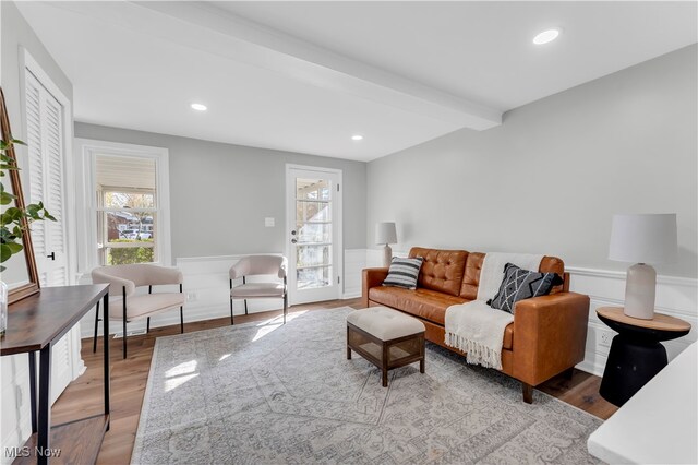 living room with beam ceiling, plenty of natural light, and light wood-type flooring