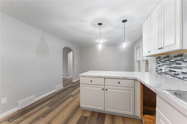 kitchen with decorative light fixtures, white cabinetry, dark wood-type flooring, and kitchen peninsula