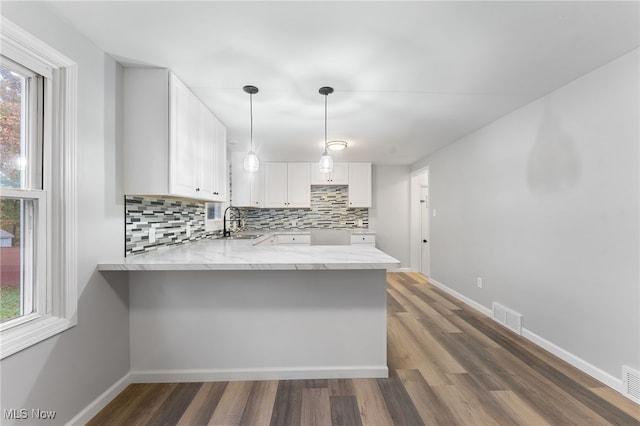 kitchen with white cabinets, kitchen peninsula, and plenty of natural light